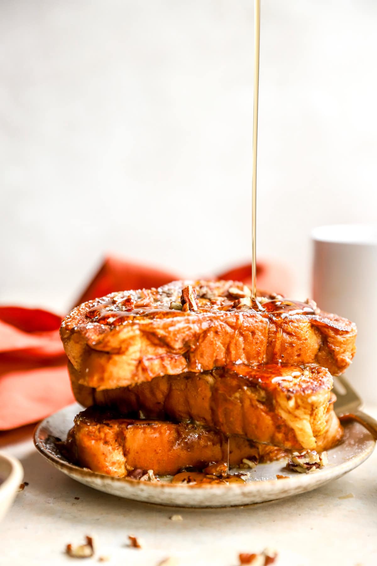 Maple syrup being drizzled over a stack of pumpkin French toast.