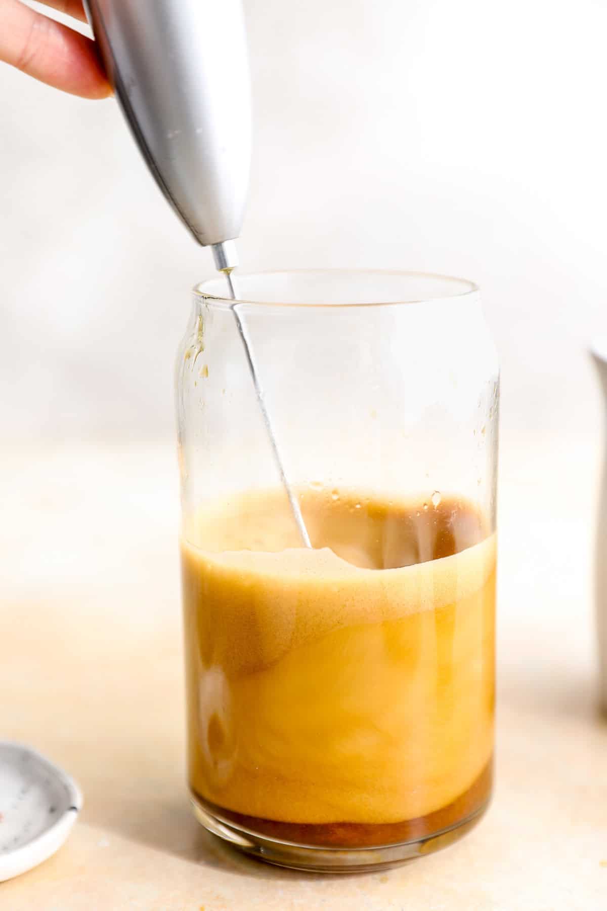 An immersion blender blending a whipped espresso.