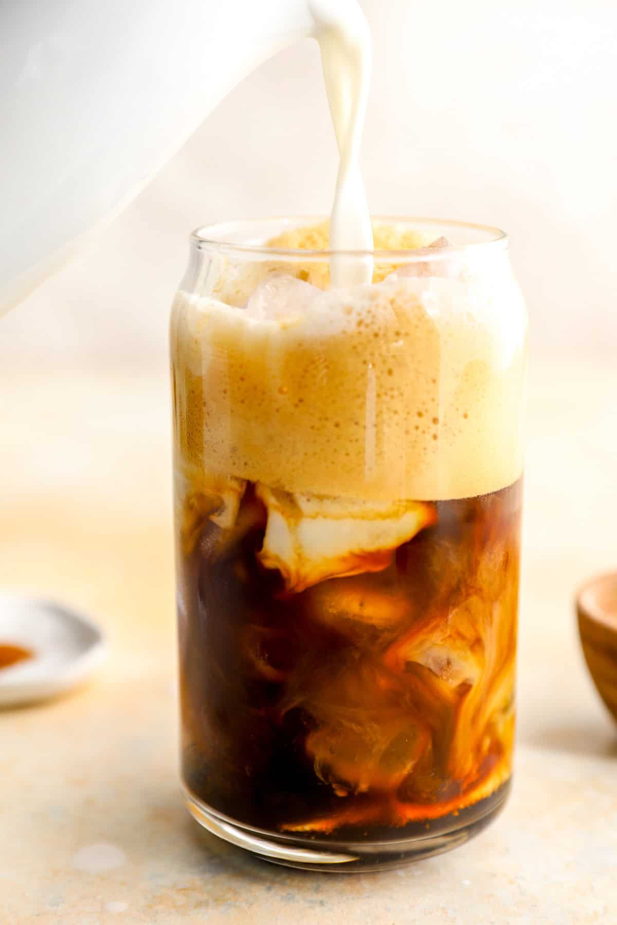 Milk being poured into a glass of espresso.
