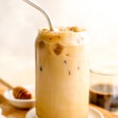 A sea salt honey latte in a glass, a metal straw sticking out.