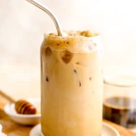 A sea salt honey latte in a glass, a metal straw sticking out.